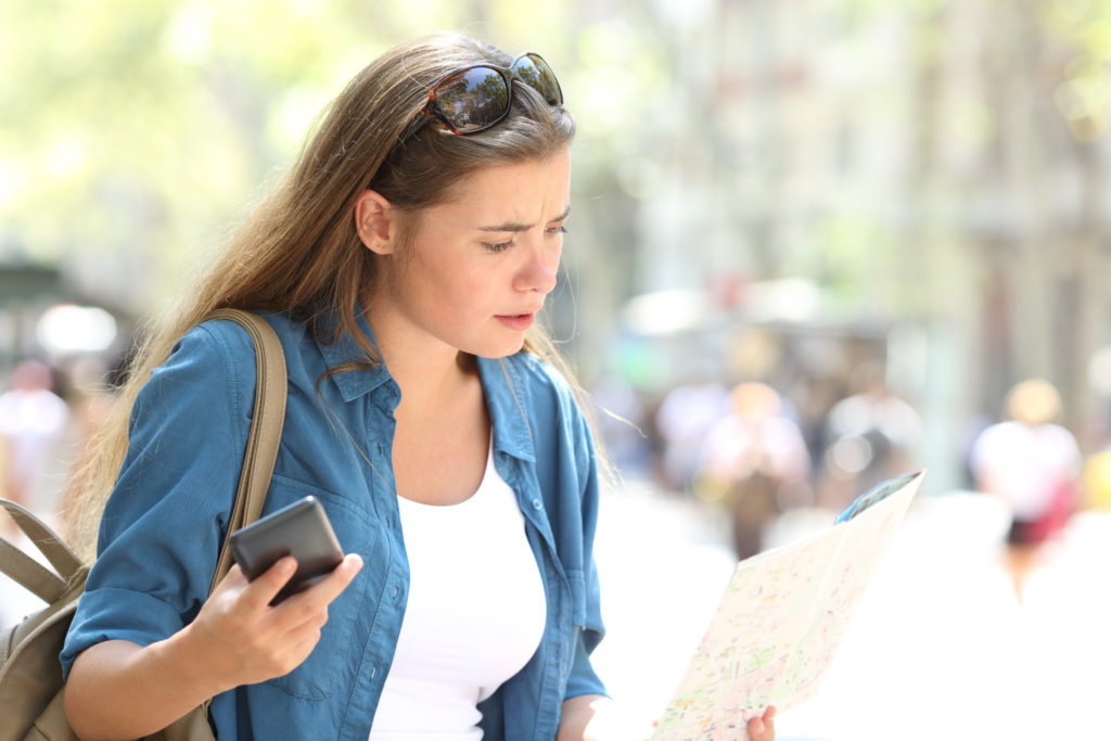 Tourist looking confused at a map and holding up her phone