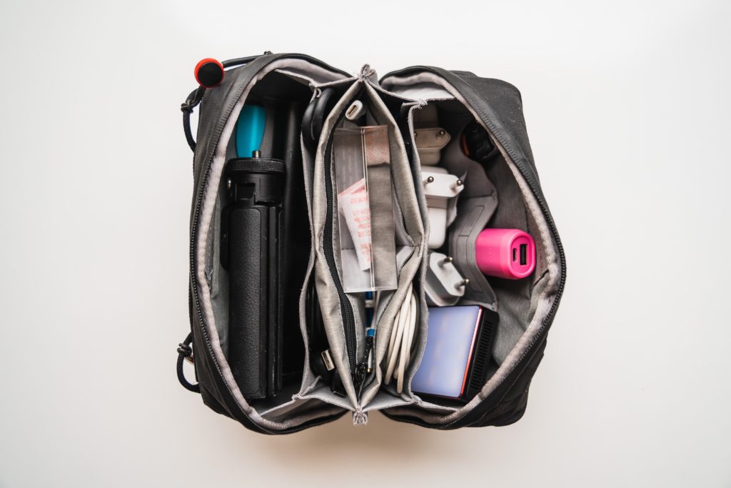 Bird's eye view into an open carry on bag filled with cables, chargers, and a tripod