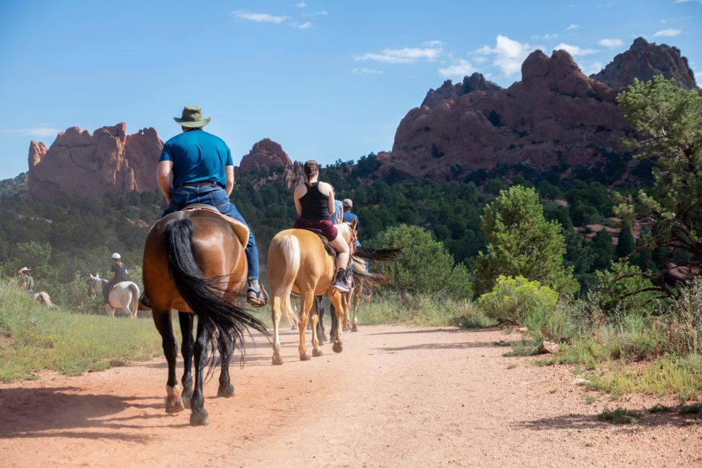 Three people horseback riding in Garden of the Gods, Colorado