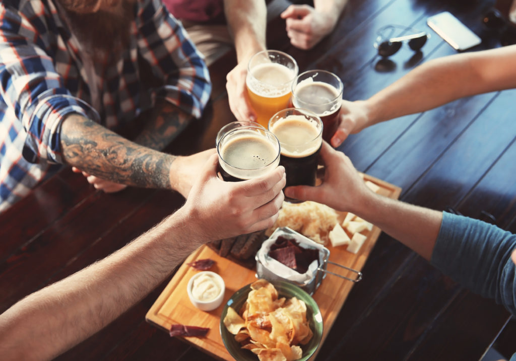 Bird's eye view of friends clinking full beer glasses