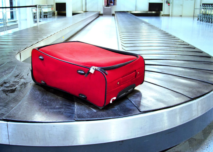 Single red suitcase on an otherwise empty baggage carousel