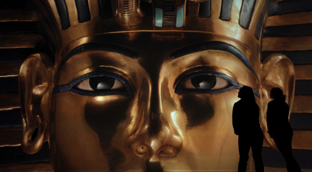 Beyond King Tut: The Immersive Experience, showing a silhouette of a person looking at a close-up of a sarcophagus  