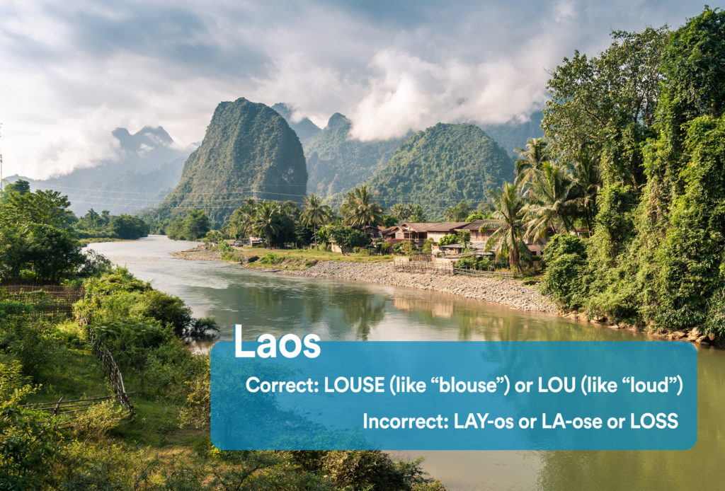 Jungle, rock formations, and a house along a river in Laos with graphic overlay showing the correct and incorrect way to pronounce "Laos"