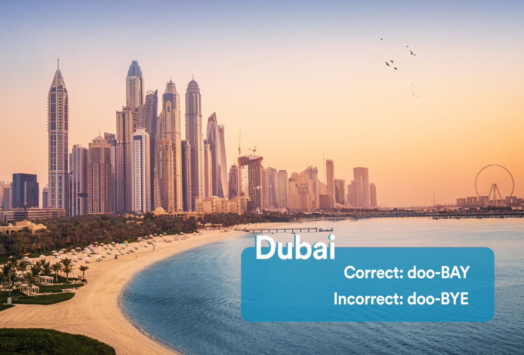City skyline and coast of Dubai with graphic overlay showing the correct and incorrect way to pronounce "Dubai"