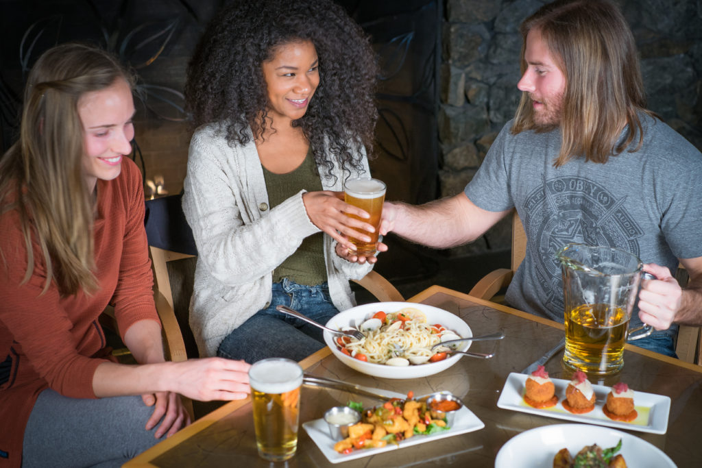 Three friends enjoying food and beer at a restaurant