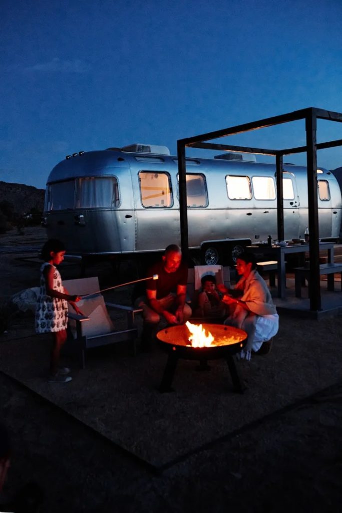 Family roasting marshmallows at campground in front of airstream at Autocamp Cape Code