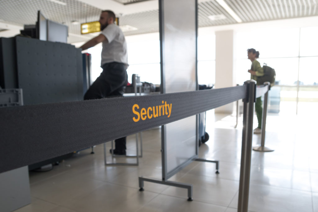 Two people standing behind a security rope at an airport