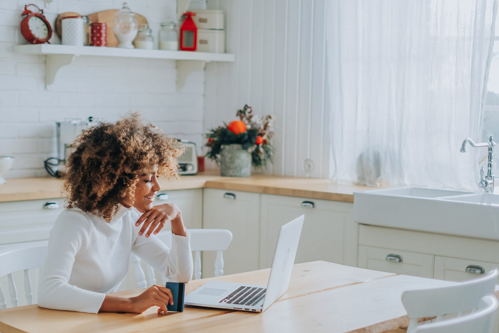 Woman online shopping in kitchen