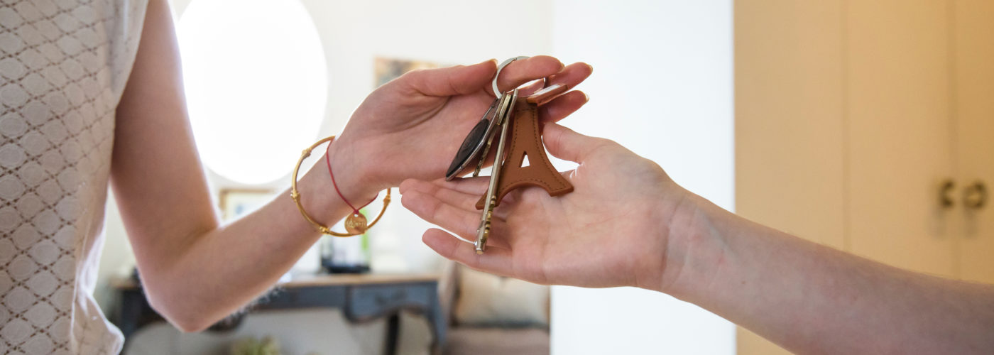 Close up of hands handing off keys to a house