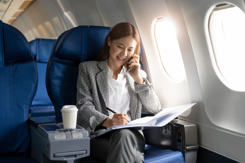 Woman talking on a cellphone and writing in a notebook on an airplane