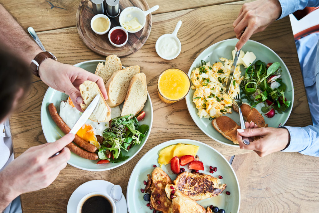 Aerial view of full breakfast table with two people eating