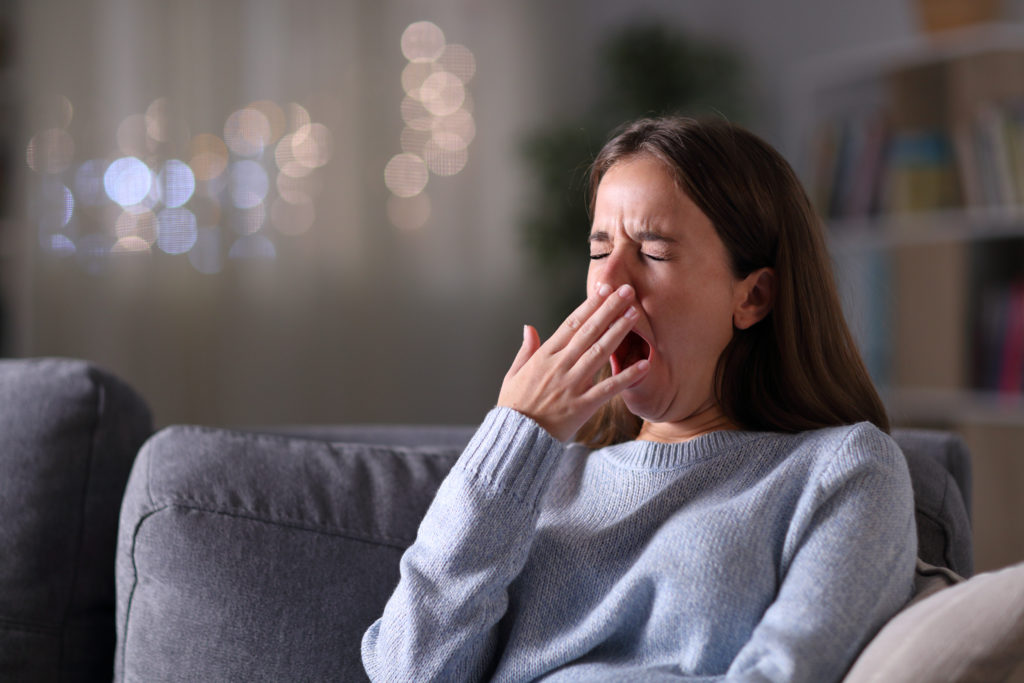 Woman sitting on couch and yawning