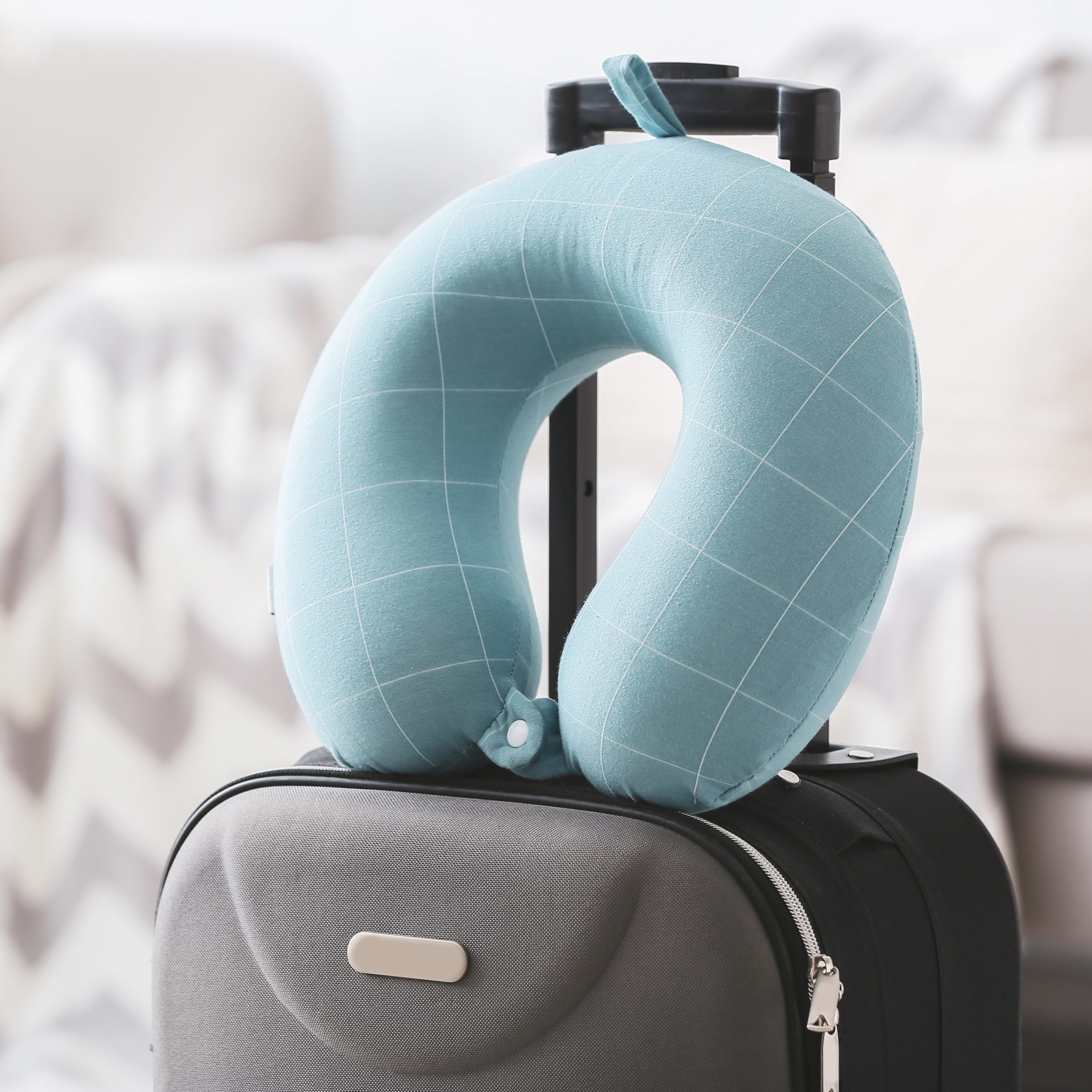 Blue classic neck pillow on top of grey suitcase