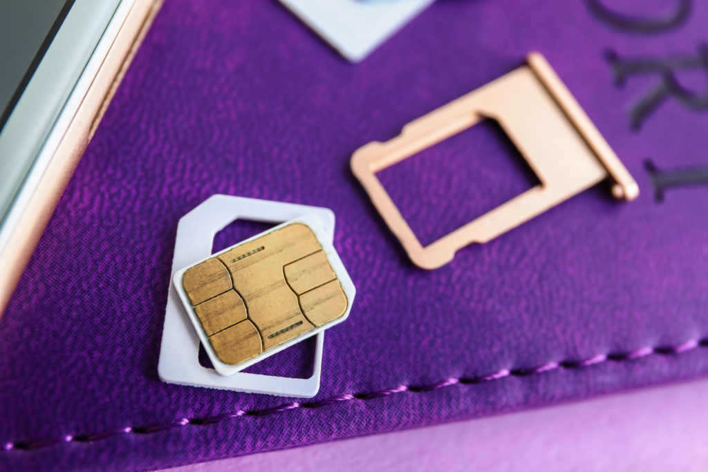 International sim card and sim card tray on top of a passport covered in a purple cover