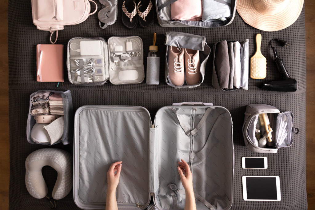 Overhead view of open empty suitcase surrounded by travel gear and packing cubes