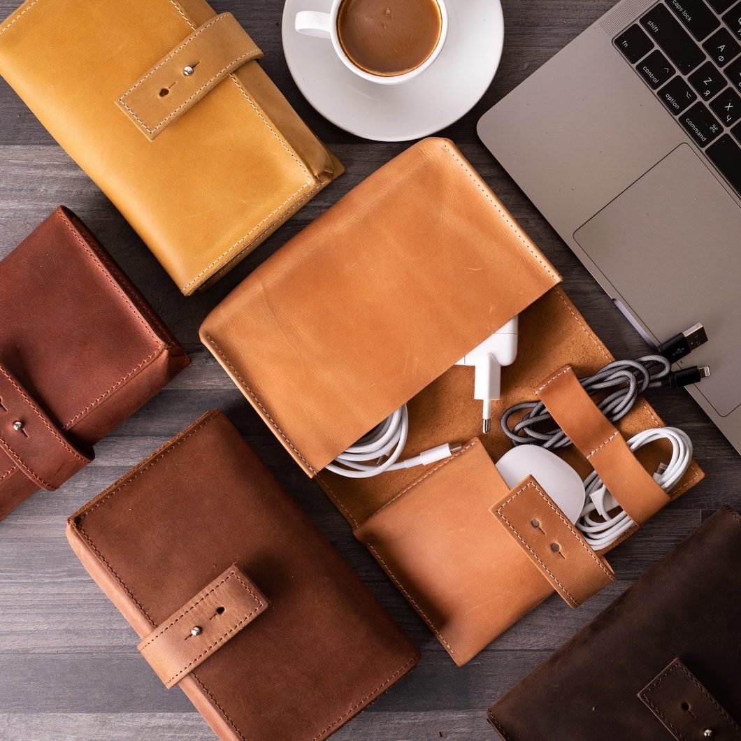 Multiple leather cable organizers on a table around a laptop
