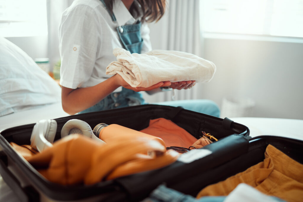 Close up of person putting clothes into a suitcase