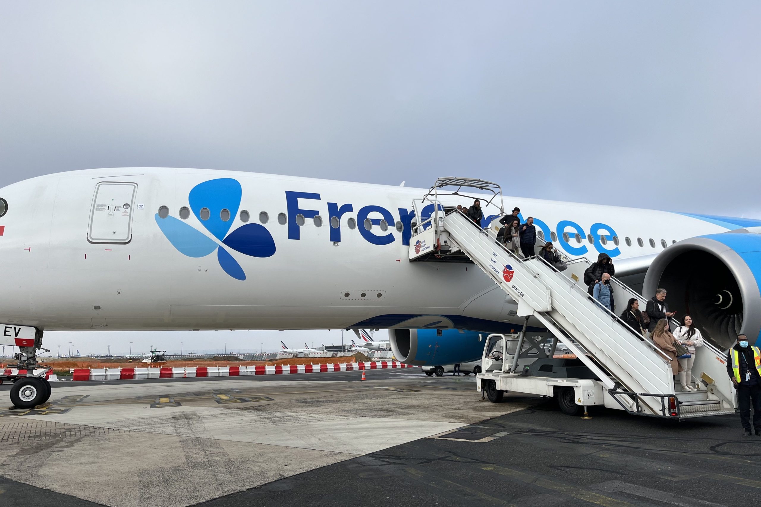 People deplaning onto the runway off a French bee airplane