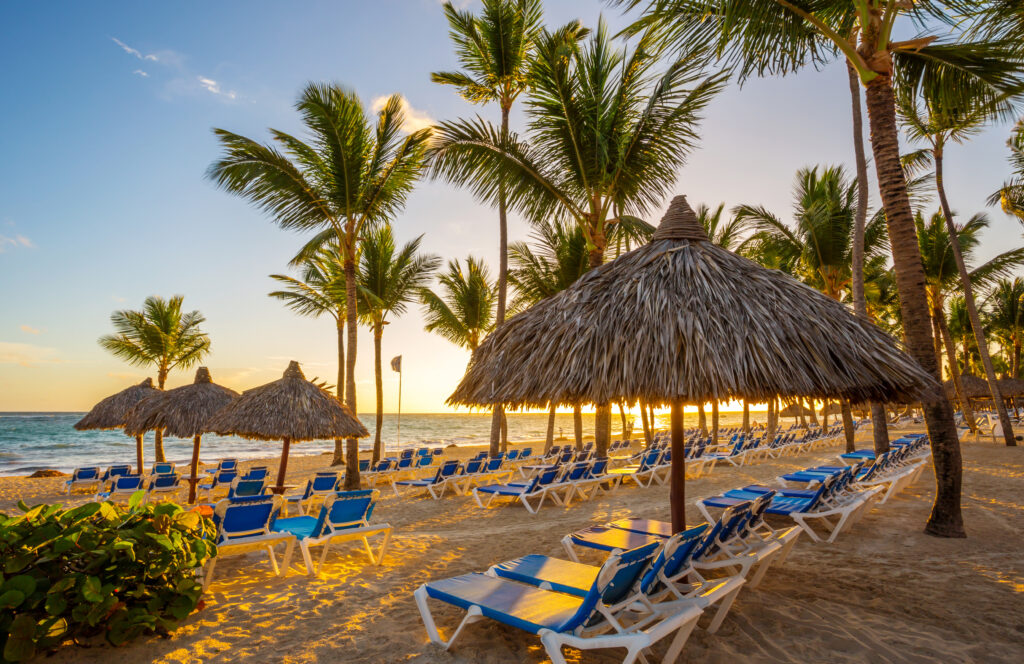 Beach with lounge chairs and palm trees at sunset in Punta Cana, Dominican Republic