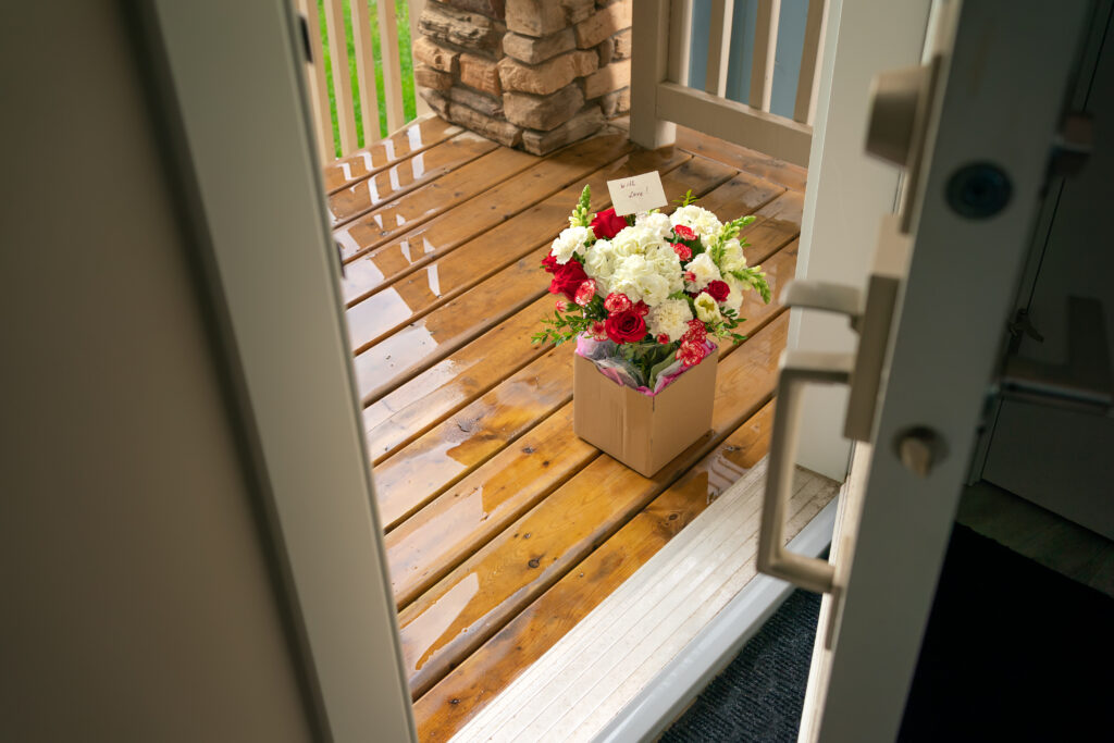 Bouquet of roses left at someone's doorstep, as seen from inside the house through the front door