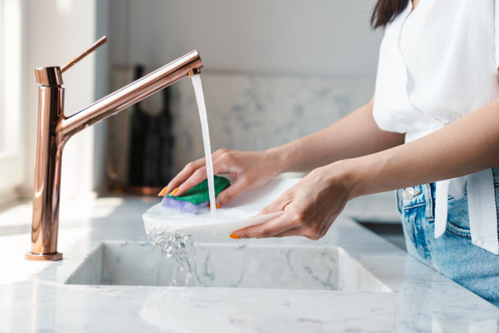 Close up of person cleaning dishes in sink