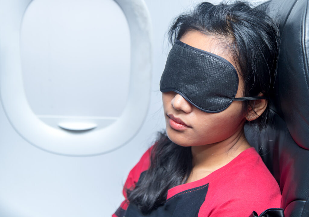 Close up of woman sleeping on an airplane wearing an eye mask