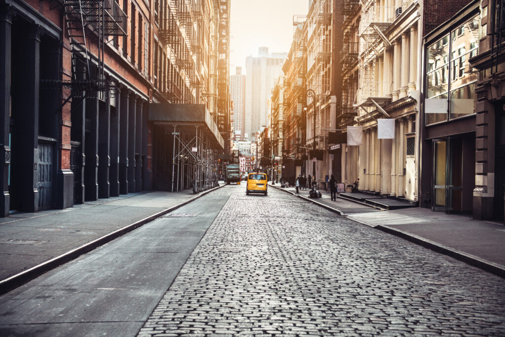 Taxi driving down empty stone street in New York City, New York, United States