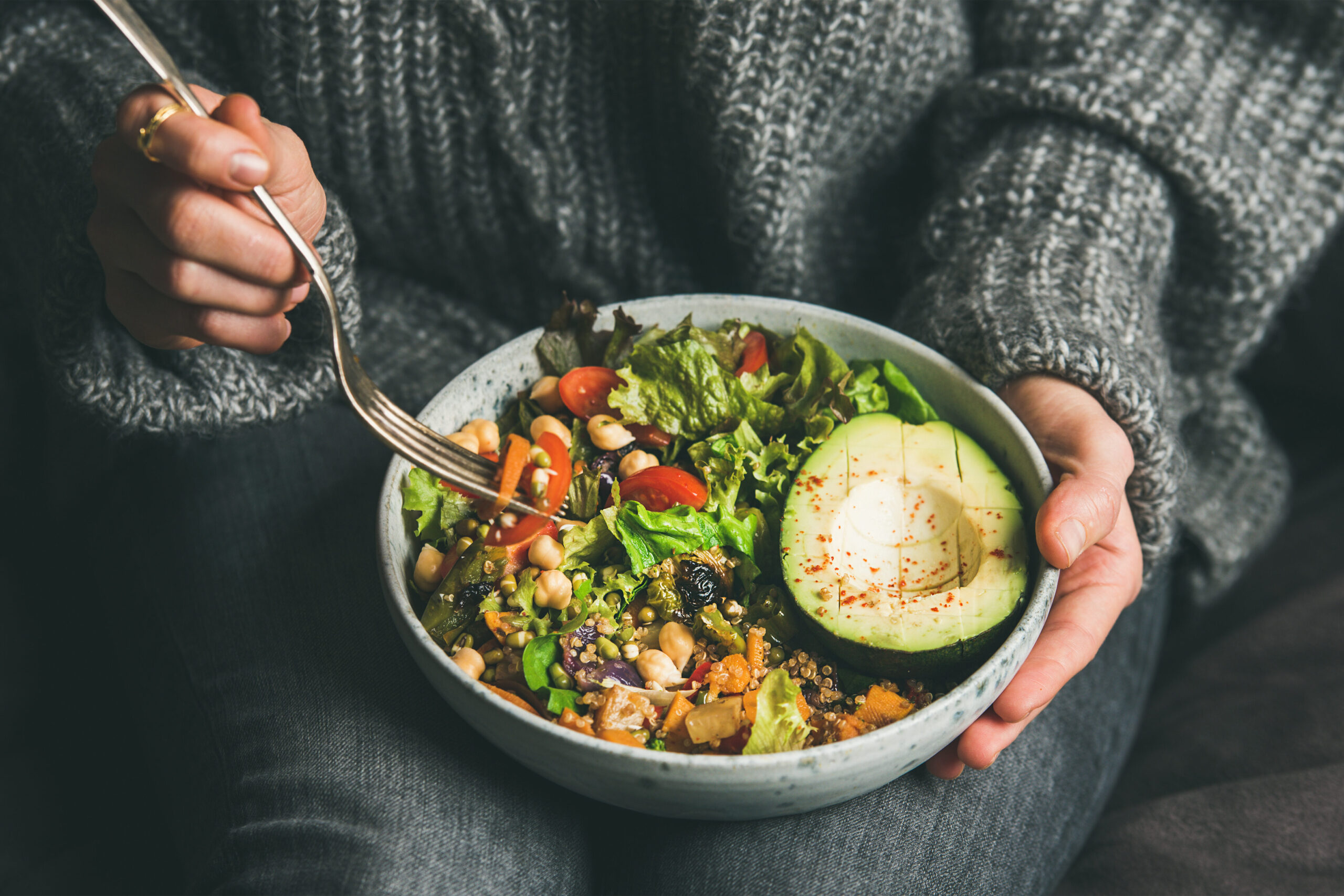 Close up of person holding bowl of lettuce and chickpeas and avocado