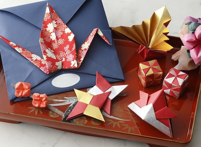 Small ceramic plat with several pieces of origami and a blue envelope on top