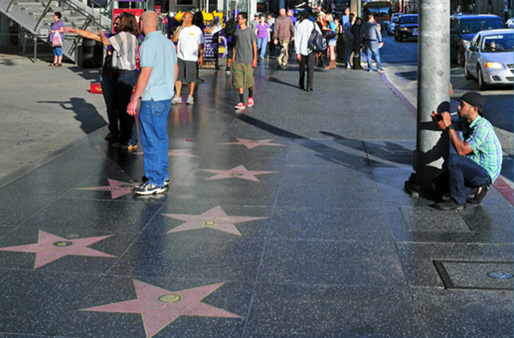 Person photographing tourists at the Hollywood Walk of Fame in Los Angeles