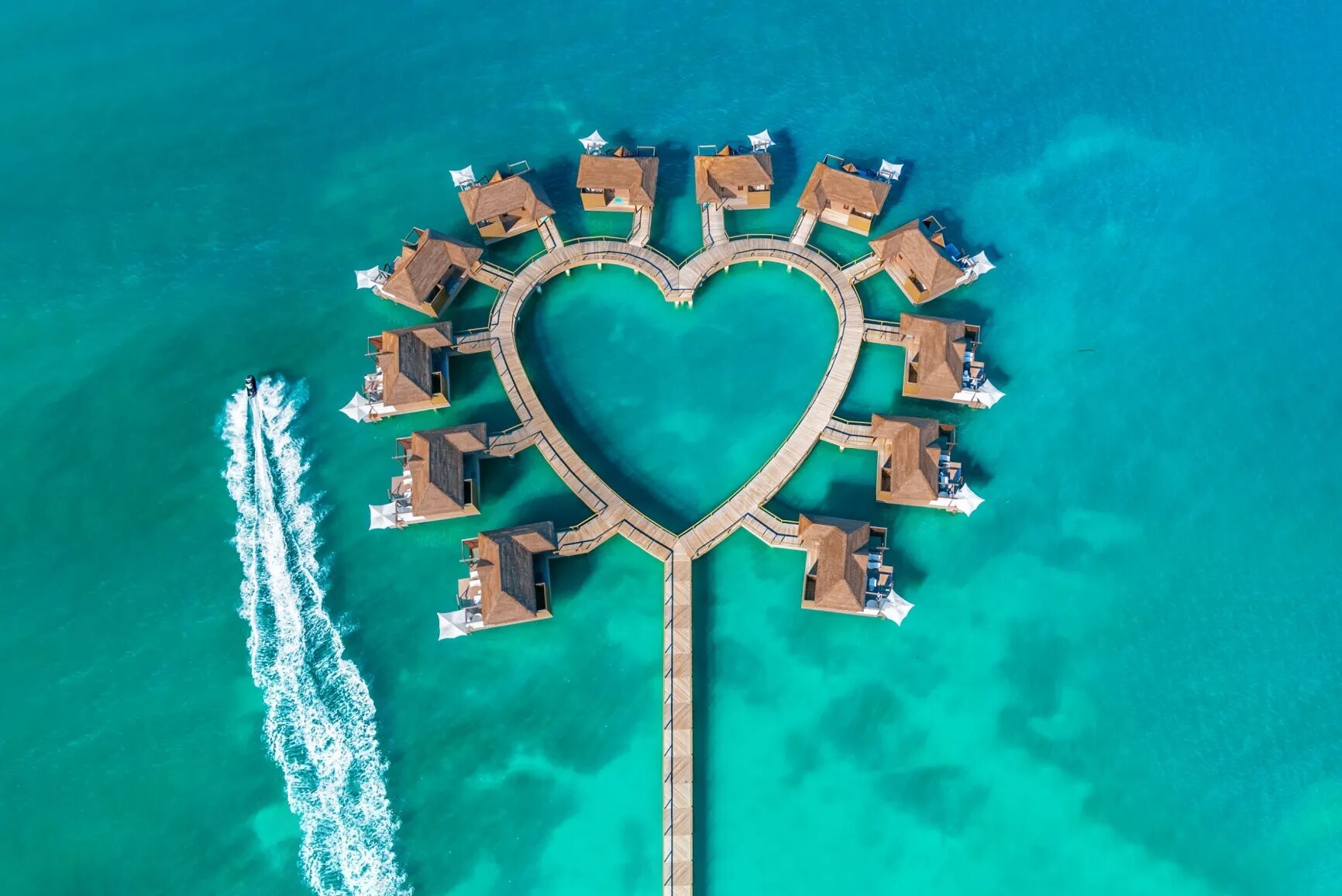 Aerial view of the overwater bungalows and villas gathered around a heart-shaped boardwalk at Sandals South Coast in Jamaica