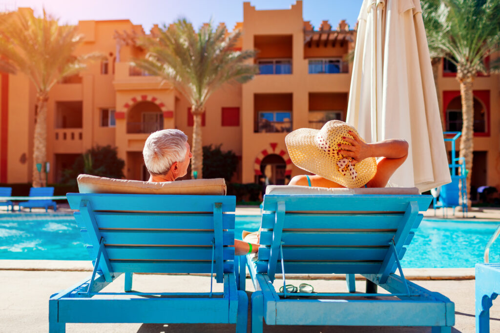 Senior couple relaxing together by the pool at a hotel on a sunny day