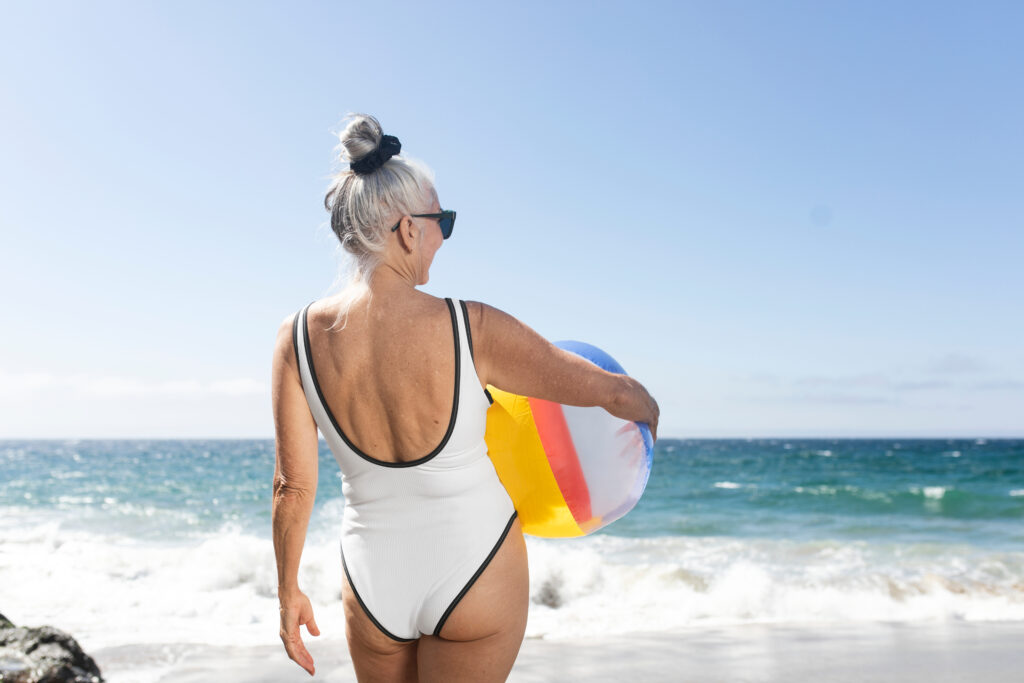 Elderly woman wearing a one piece swimsuit and holding a beach ball
