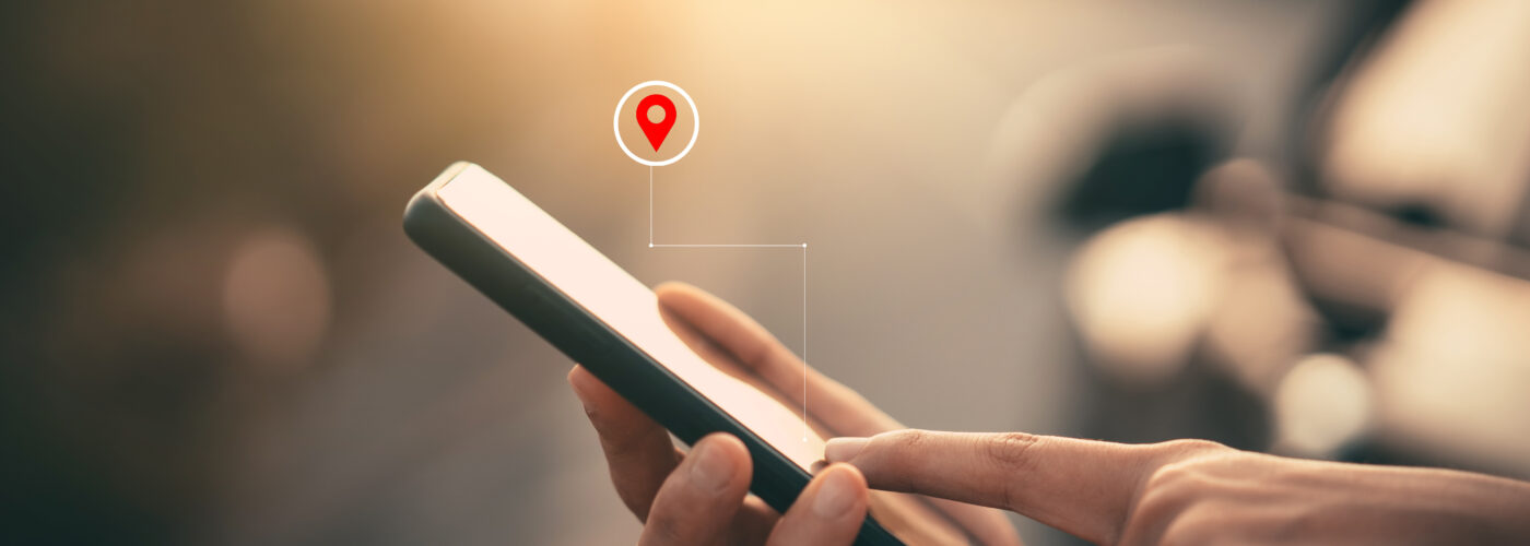 Close up of person using their smartphone with a graphic overlayed showing a location pin