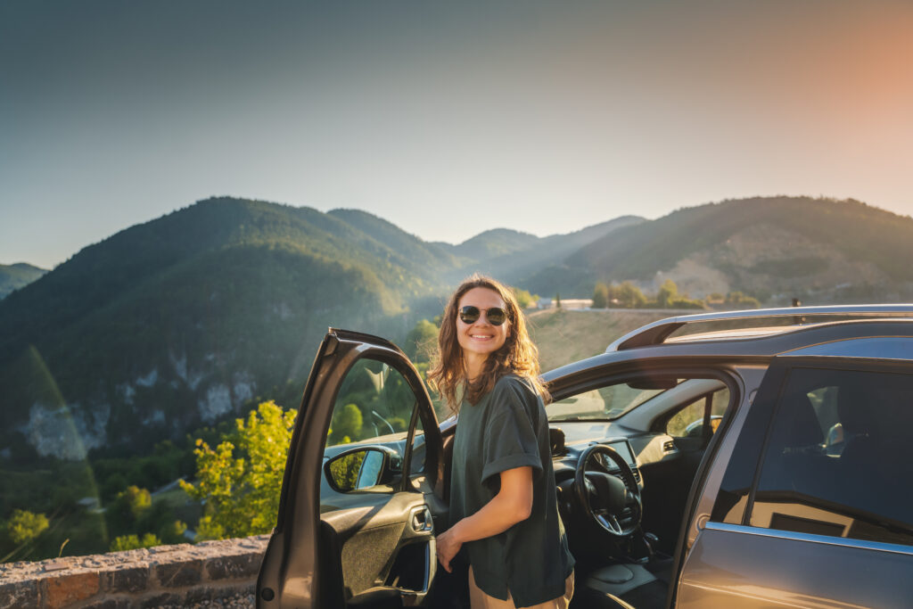 Women stepping out of car at an overlook with a view of mountains and forest