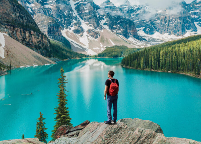 Person standing, overlooking Moraine Lake and surrounding mountains in Banff, National Park