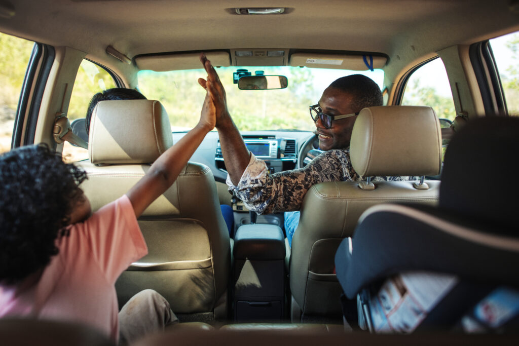 Father high-fiving daughter in car on family road trip