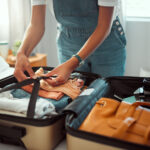Close up of person packing luggage on bed