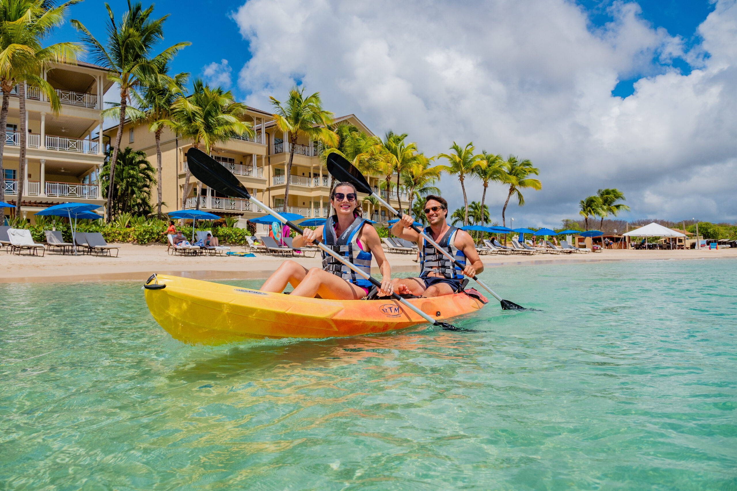 Happy couple kayaking off the beach at The Landings Saint Lucia on a sunny day
