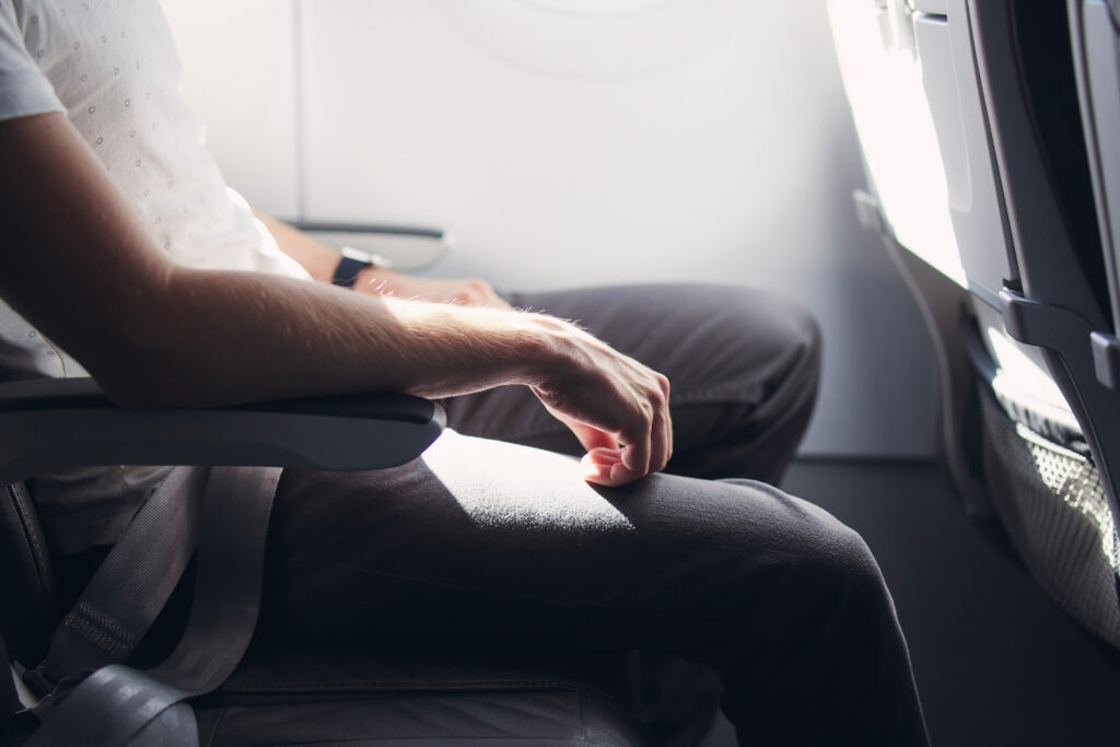 Close up of person resting arms on armrest in the middle seat of an airplane row