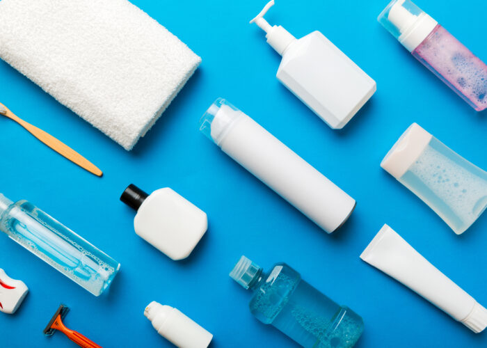 Overhead view of several travel toiletries laid out on a blue background