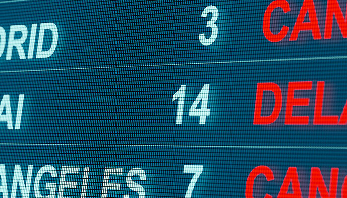 Close up of arrivals board showing flights from several destinations either cancelled or delayed