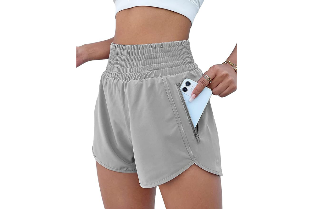 Female wearing beige shorts putting blue phone in the pocket