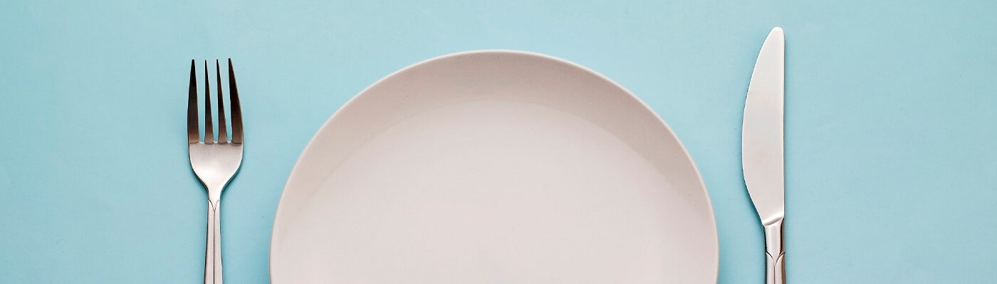 Empty fork, plate, and knife on blue background