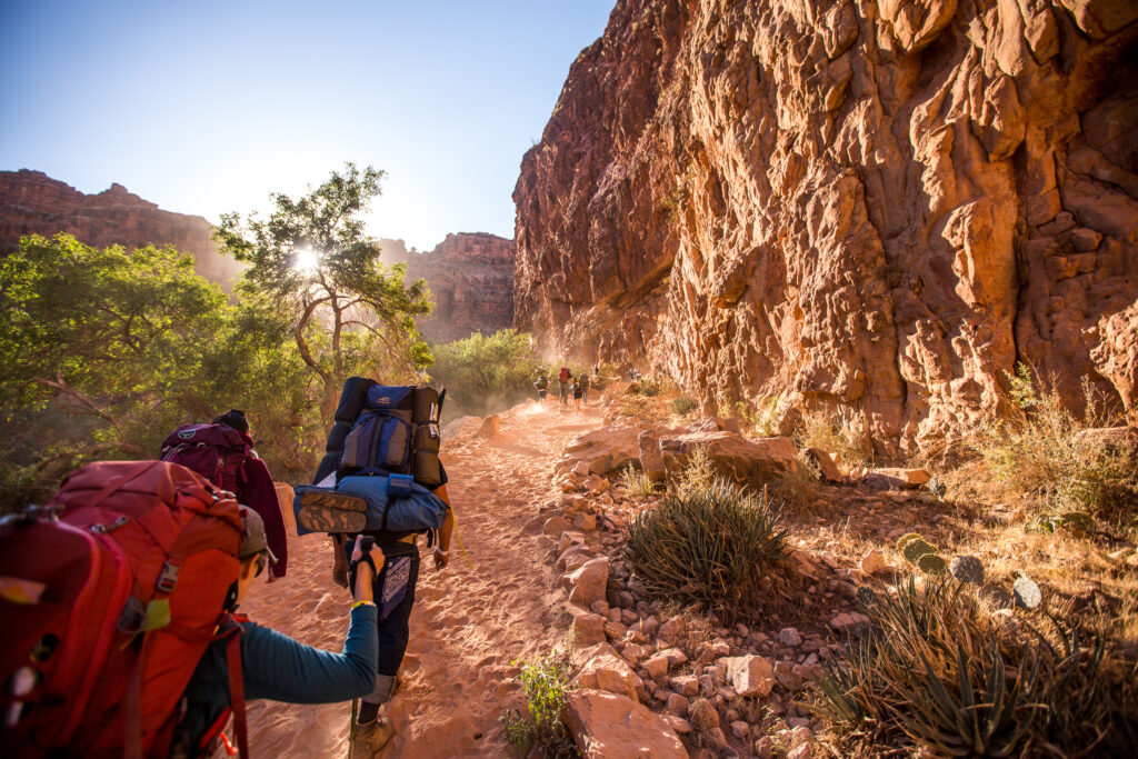 Hiking group walking through Grand Canyon with hiking backpacks
