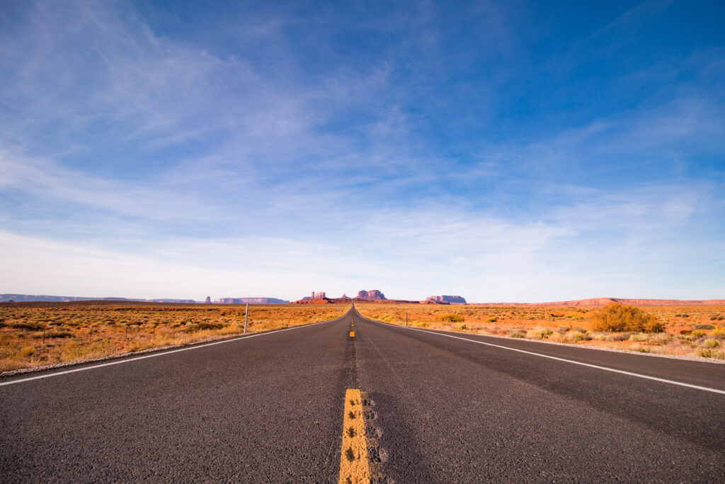 Road leading through Monument Valley, a popular road trip route to the Grand Canyon