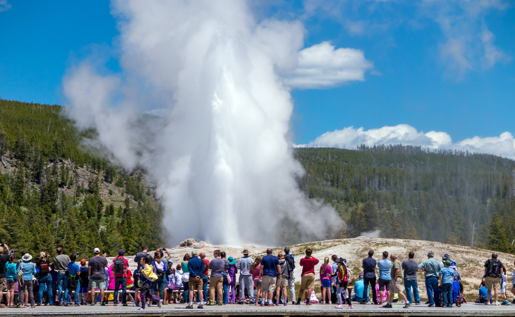 Tourists watching the Old Faithful erupting in Yellowstone National Park.