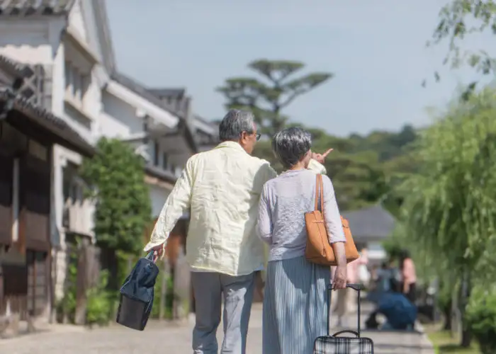 A couple carrying luggage and walking through a scenic destination