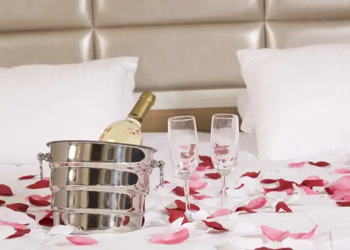 hotel bed with roses and sparking wine