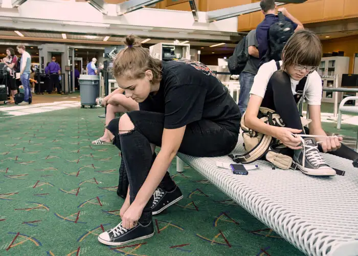 Travelers put their shoes back on after clearing airport security